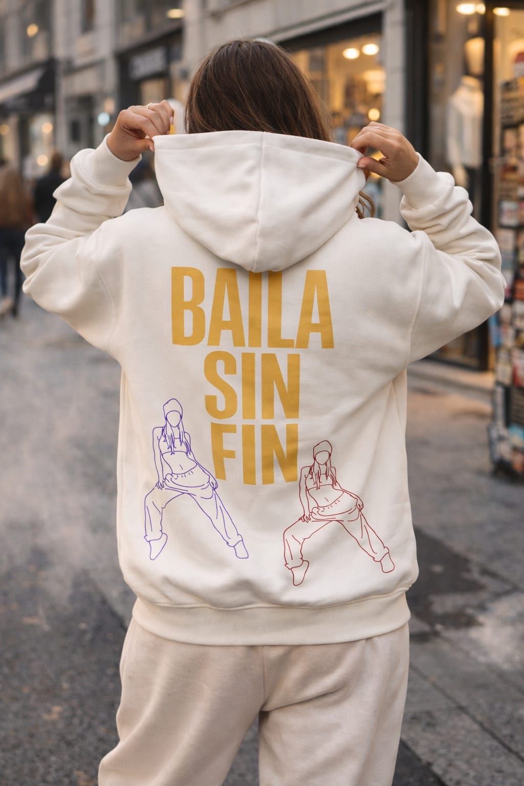 Model wearing white oversized hoodie with “Baila sin fin” print, back view